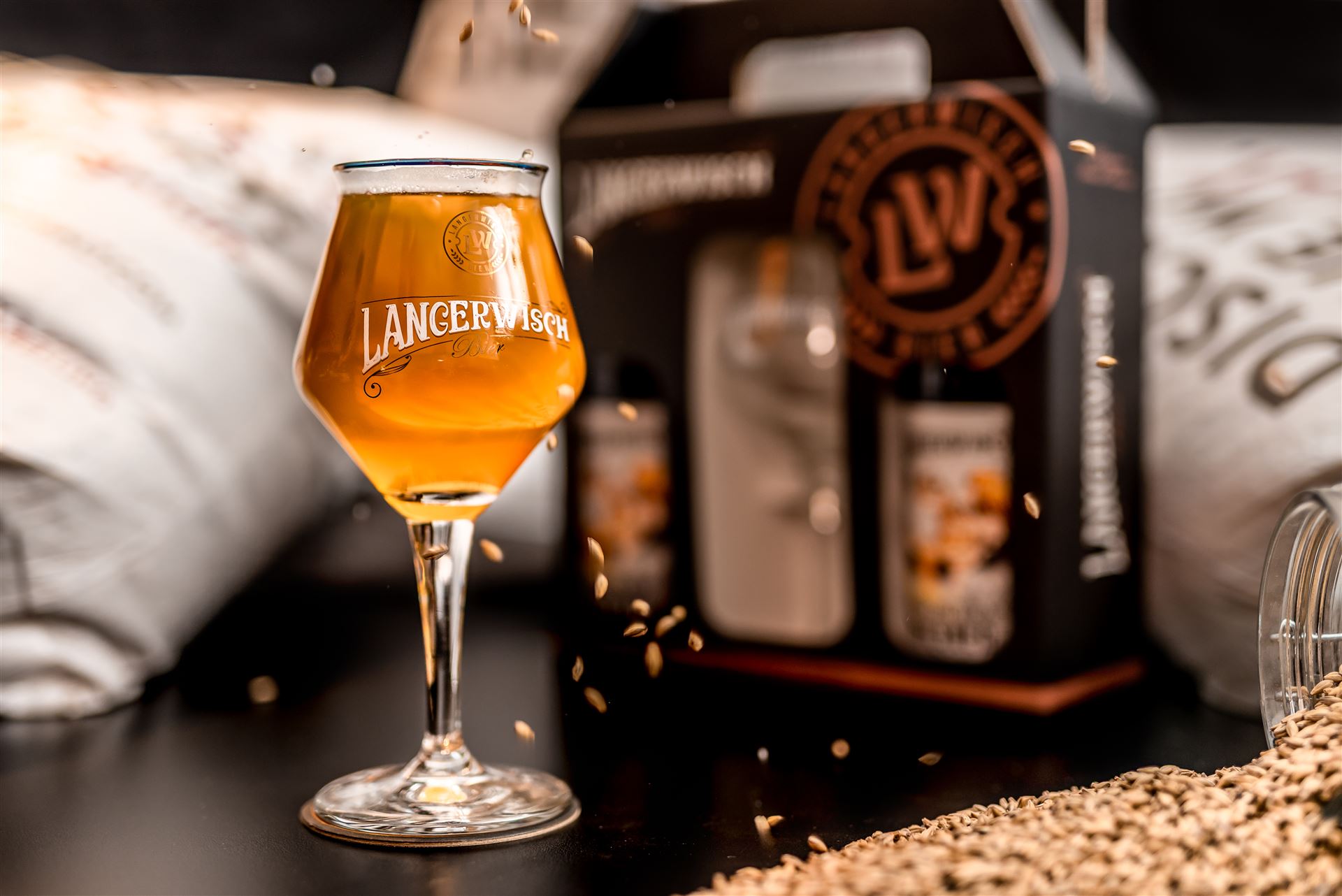 Taça de chopp artesanal Langerwisch servida ao lado de garrafas e malte